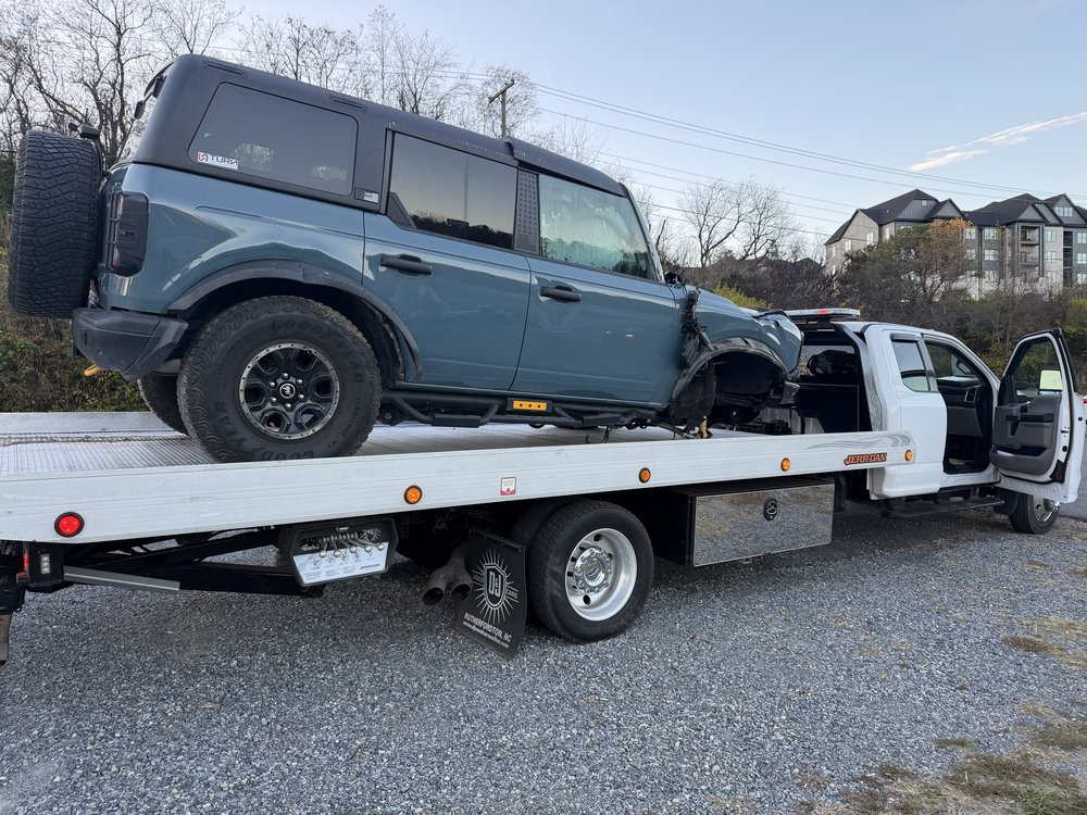 Damaged Ford Bronco secured on a D&K flatbed tow truck
