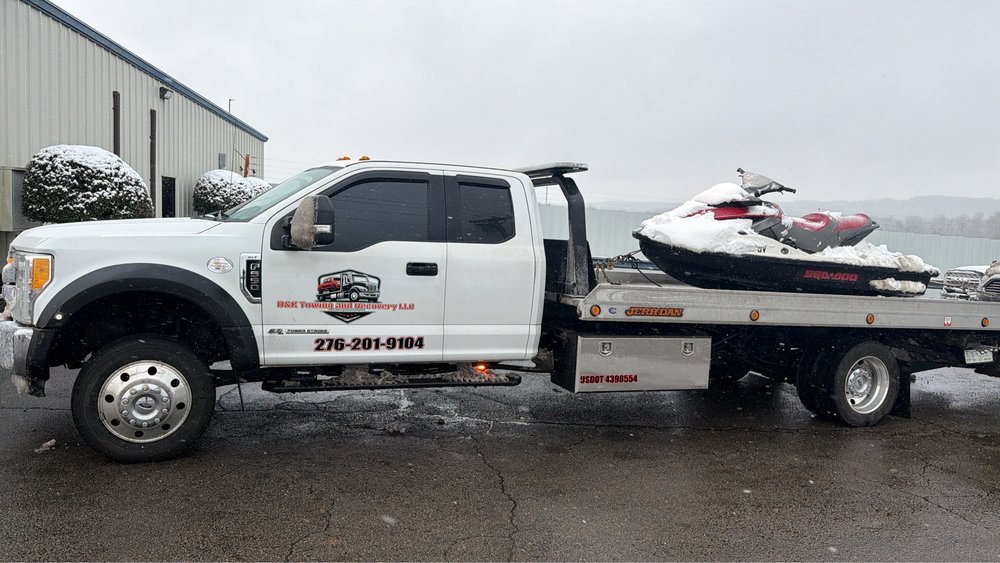 D&K flatbed tow truck transporting a jet ski in winter conditions