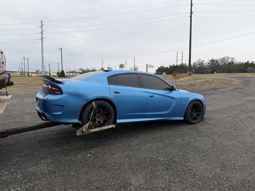 Blue Dodge Charger being winched onto a tow truck